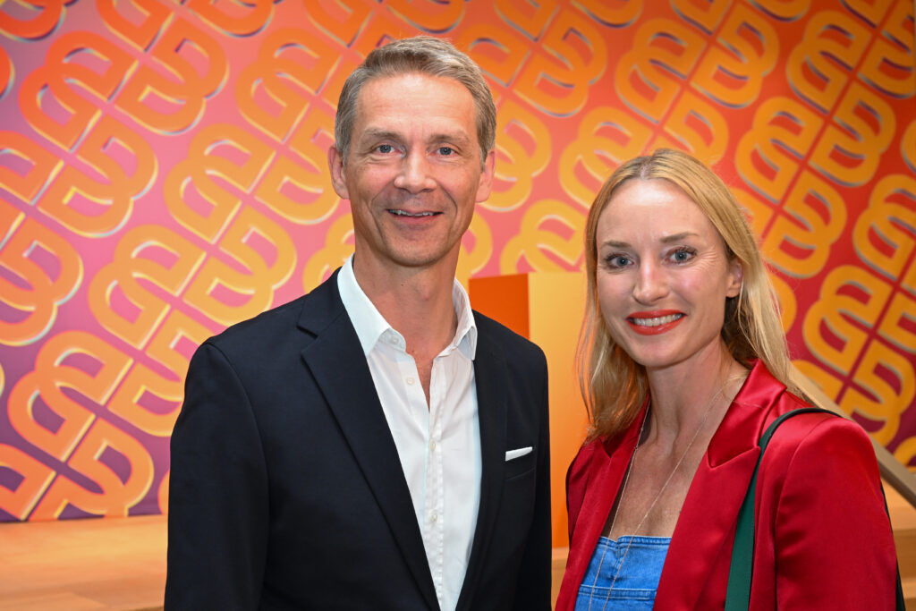Holger Blecker als CEO von Breuninger und Petra Winder stehen nebeneinander vor dem Logo von Breuninger