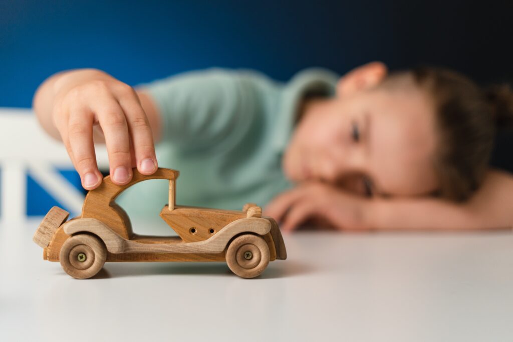 Junger Bub spielt mit Holzauto.