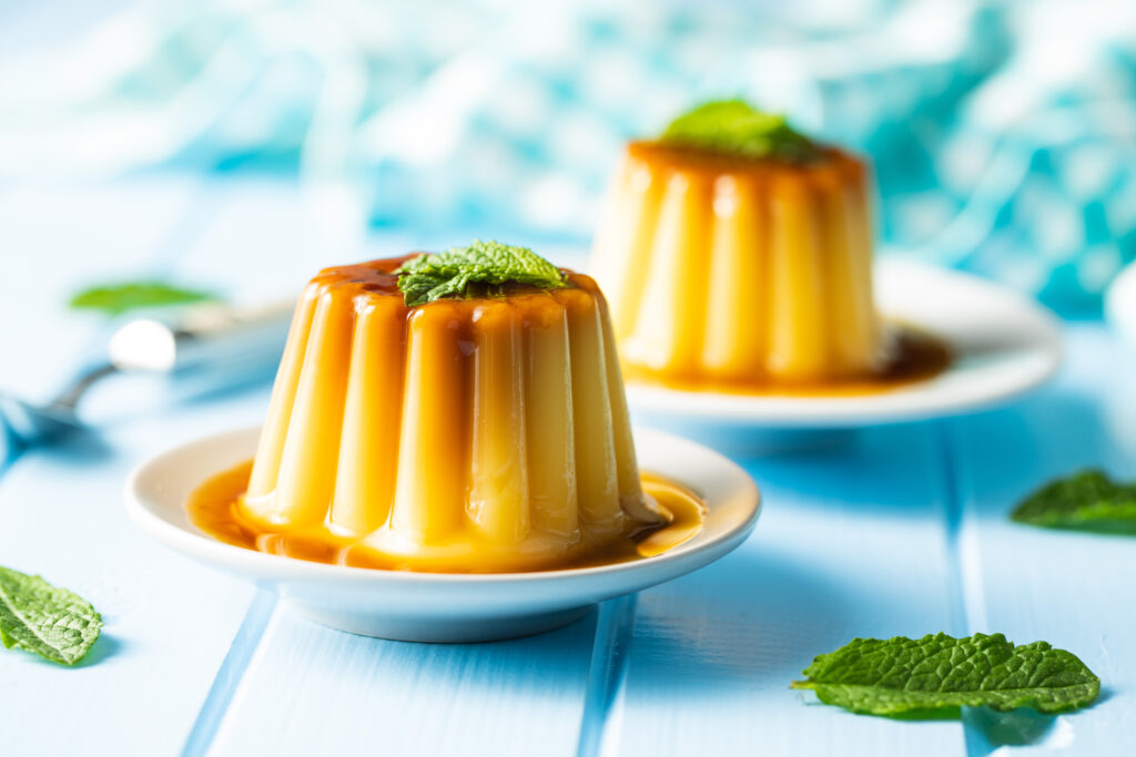 Zwei Puddings mit Karamellsoße und Minzblättern.