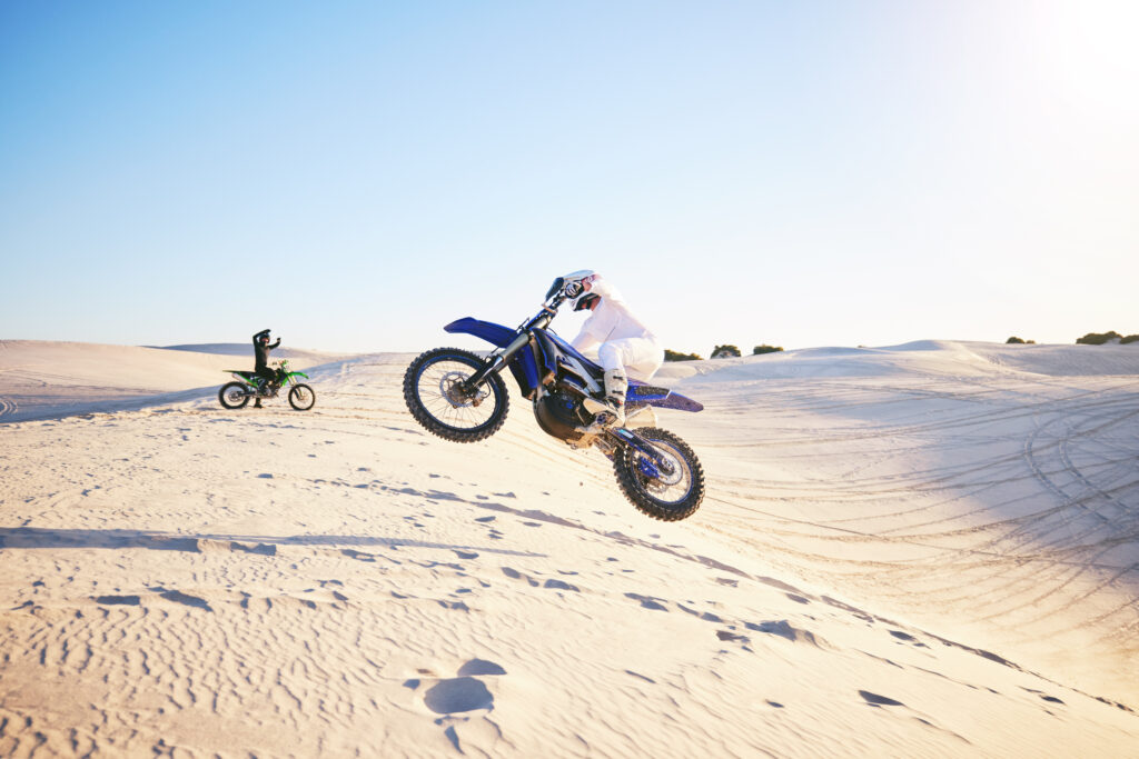 KTM Wüste und zwei Motorradfahrer. Einer davon macht einen Luftsprung mit seinem Motorrad