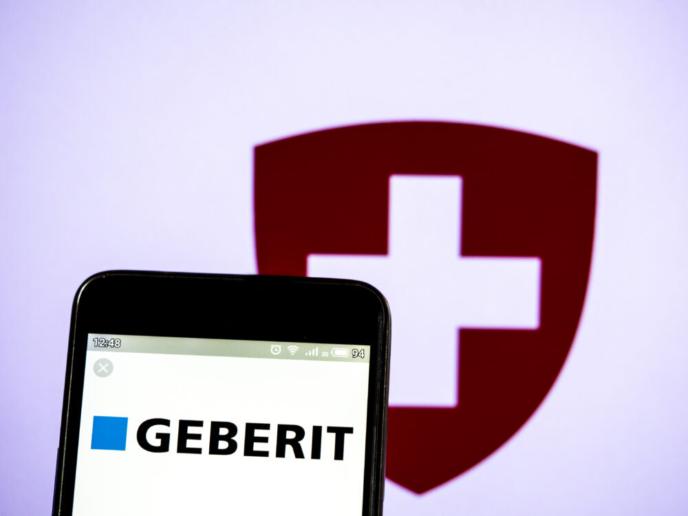 Logo von Geberit auf einem Handy und die Fahne der Schweiz