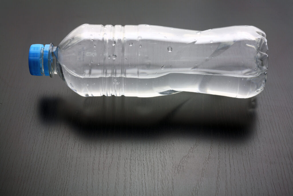 grauer Hintergrund und eine Plastikfasche mit einem blauen Verschluss
