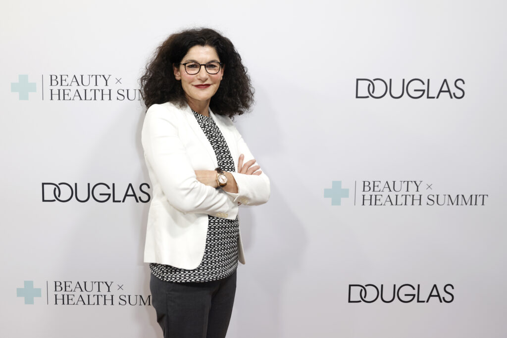 Tina Müller als CEO von Douglas vor einem Douglas Werbeplakat