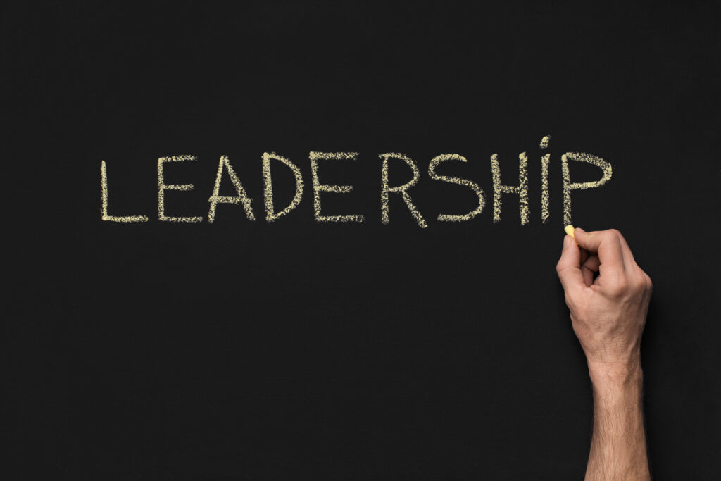 Hand schreibt Leadership auf eine schwarze Tafel
