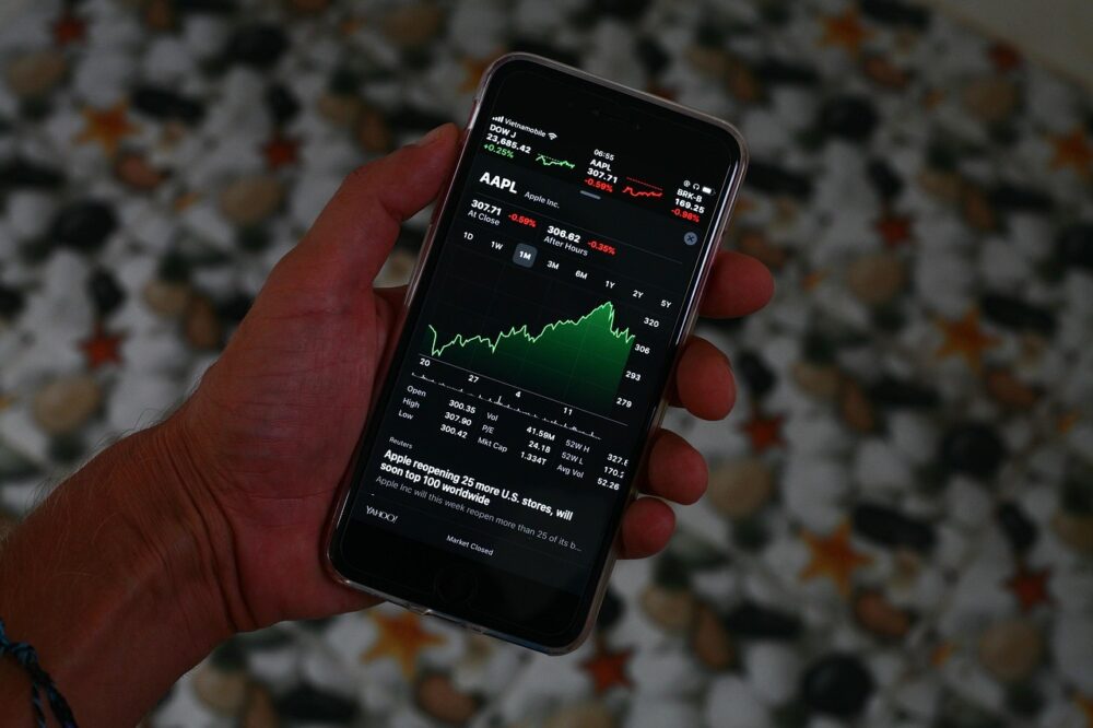Ein Smartphone mit Börsenkursen auf dem Display liegt neben einem Laptop und symbolisiert das Trade Republic Ranking im Neobroker-Vergleich – Foto: sergeitokmakov / Pixabay